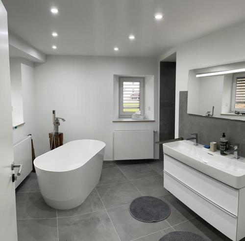 a white bathroom with a tub and two sinks at Ferienhaus De Luxe in Engen