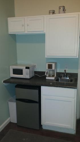 a kitchen with white cabinets and a sink and a microwave at Pine Street Studios in Florence