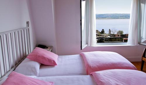 a couch with pink pillows in a room with a window at Hotel Rural Salvatierra in Salvatierra de Tormes