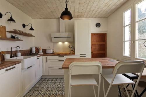 une cuisine avec une table en bois et des armoires blanches dans l'établissement La Villa d'Anna, une décoration très tendance !, à Primelin