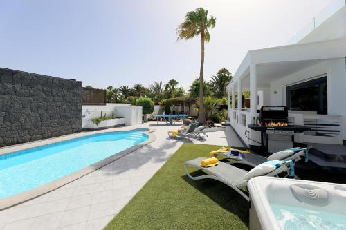 a backyard with a swimming pool and a house at Casa Nublo - 3 Bedroom family villa - Great sea views from rooftop terrace in Puerto Calero