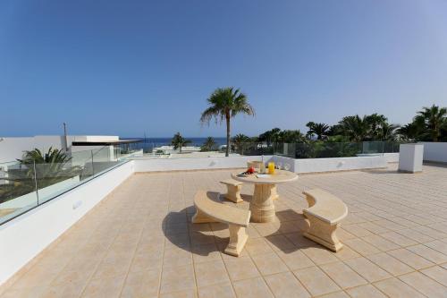 a patio with a table and benches on a roof at Casa Nublo - 3 Bedroom family villa - Great sea views from rooftop terrace in Puerto Calero