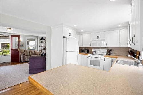 a kitchen and living room with white cabinets and a table at Glades Manor: Minot Beach Scituate in Scituate