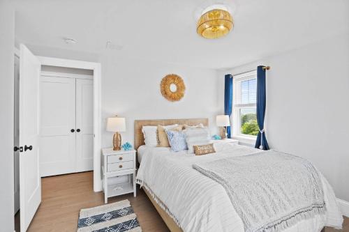 a white bedroom with a bed and a window at Sandy Clydesdale: Sagamore Beach Sandwich in Sandwich