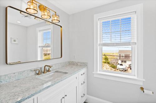 a white bathroom with a sink and a mirror at Sandy Clydesdale: Sagamore Beach Sandwich in Sandwich