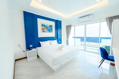 1 dormitorio con 1 cama grande y pared azul en Marble Arch De Loei Hotel en Loei