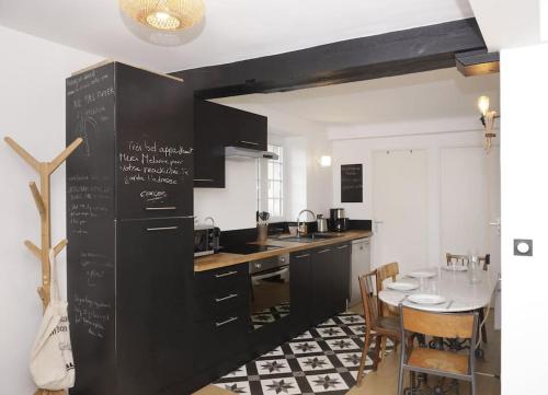 une cuisine avec des armoires noires et une table ainsi qu'une salle à manger dans l'établissement Appartement Le Moulin by La Boîte En Plus, à Senlis