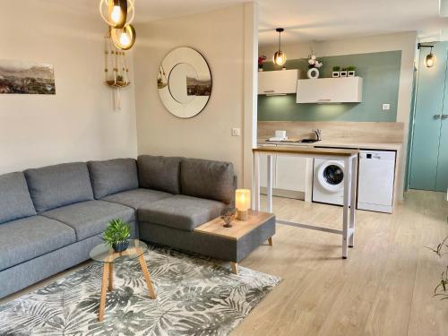 ein Wohnzimmer mit einem blauen Sofa und einer Küche in der Unterkunft Appt Cosy résidence Palmareda in Tarbes