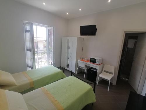 a room with two beds and a desk with a microwave at B&B Villa Agrumé in Messina