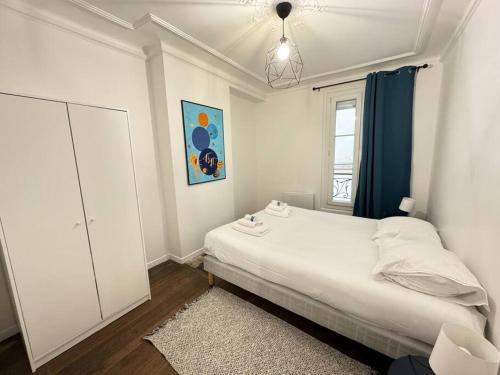 a white bedroom with a bed and a window at Magnifique Appartement - Mairie 18ème in Paris