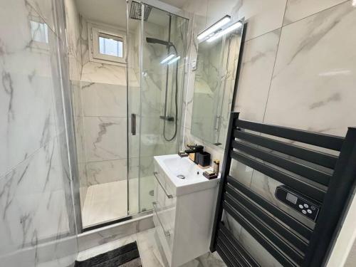 a white bathroom with a shower and a sink at Magnifique Appartement - Mairie 18ème in Paris