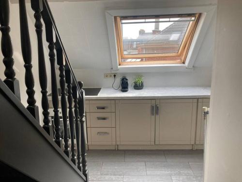 een keuken met een trap met een raam en een aanrecht bij Cozy attic apartment in Antwerpen