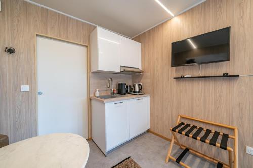 une cuisine avec des armoires blanches et une table et une chaise dans l'établissement Le Chant des Pins Lodge & Spa Tour de Keyrié, à La Mignarde