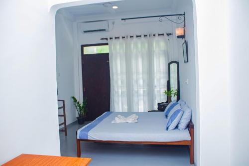 a bedroom with a bed with blue sheets and a window at Cliff house in Weligama