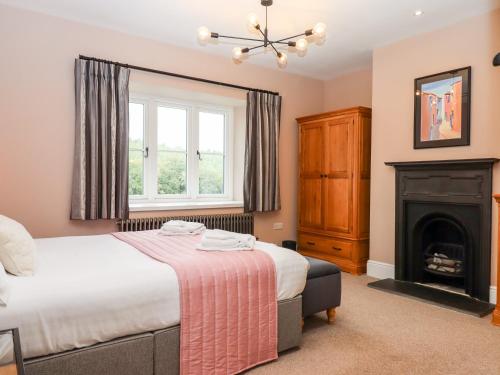 a bedroom with a bed and a fireplace at Knowle House in Okehampton