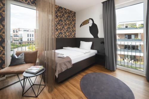 um quarto com uma cama, uma cadeira e uma janela em We rooms Hotel em Karben