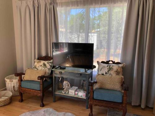 sala de estar con TV y 2 sillas en House Fynbos, 4 Bedroom house, en Bloemfontein