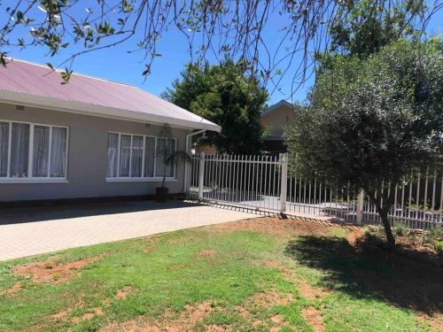 una cerca blanca frente a una casa en House Fynbos, 4 Bedroom house en Bloemfontein