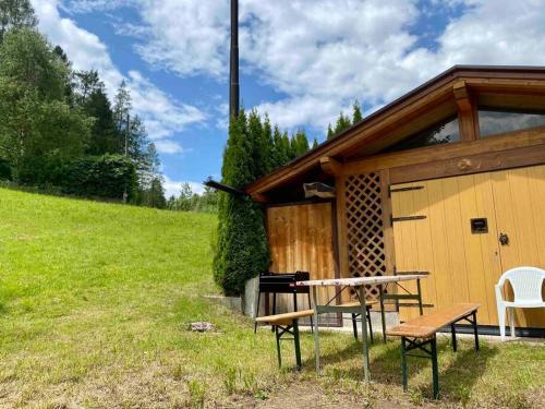 a picnic table and a bench in front of a cabin at Zirmo - Your nordic stay in Tesero