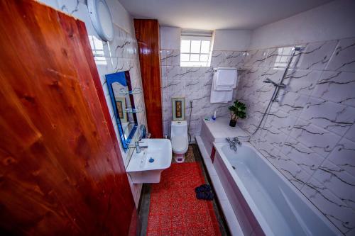 a bathroom with a sink and a tub and a toilet at DASCUS HOTELS in Kampala