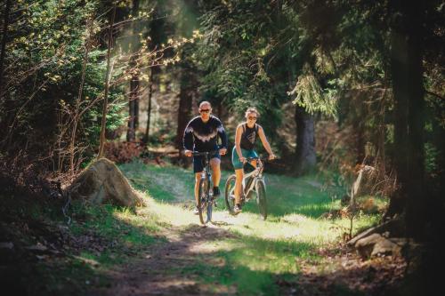 dos personas montando bicicletas en un sendero en el bosque en Czarny Kamień Resort & SPA en Szklarska Poręba