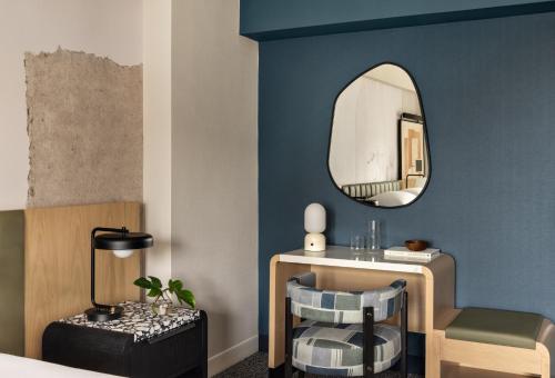 a bedroom with a mirror and a chair and a table at Kimpton Theta New York - Times Square by IHG in New York