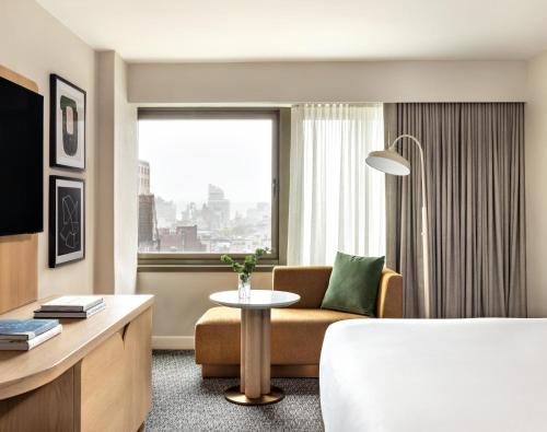 a hotel room with a bed and a table and a window at Kimpton Hotel Theta, an IHG Hotel in New York