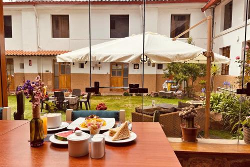 einen Tisch mit Teller mit Lebensmitteln und einem Regenschirm in der Unterkunft Hotel Monasterio San Pedro in Cusco