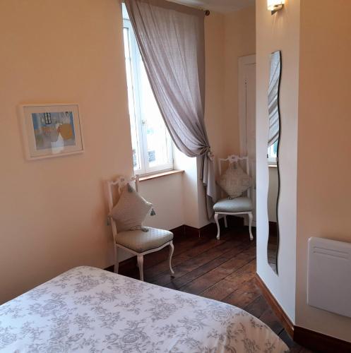 a bedroom with two chairs and a bed and a window at Domfront - Numero CINQ in Domfront