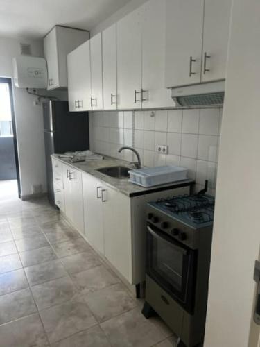 a kitchen with white cabinets and a stove top oven at Apartamento in Praia