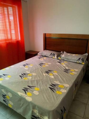 a bed in a bedroom with a bedspread with flowers on it at Apartamento in Praia