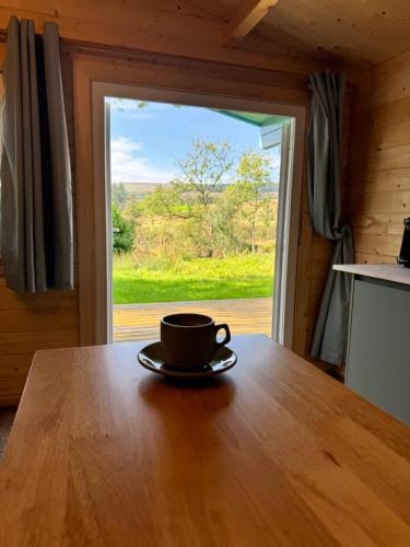 a cup of coffee sitting on a table with a window at Glenariff Forest Larch Cabin in Glenariff