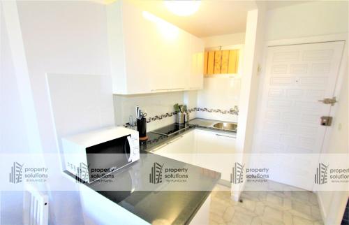 Una cocina con gabinetes blancos y encimera. en 426 Estudio en Minerva Apartamentos - Vista al jardín - Piscina y Playa, en Benalmádena
