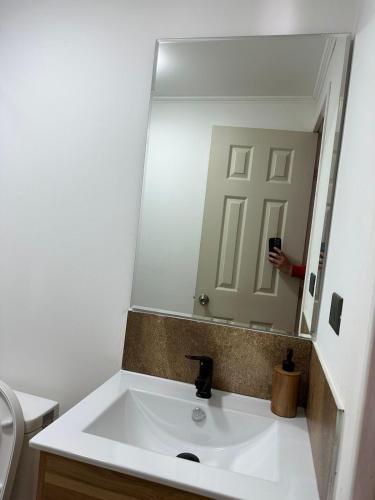 La salle de bains est pourvue d'un lavabo et d'un grand miroir. dans l'établissement Hospedaje CYR, à Temuco