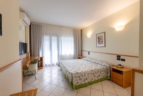 ヴィエステにあるHotel degli Uliviのベッドとテレビが備わるホテルルームです。