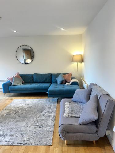 a living room with a blue couch and a mirror at Spacious Mews Apartment, Clapham in London