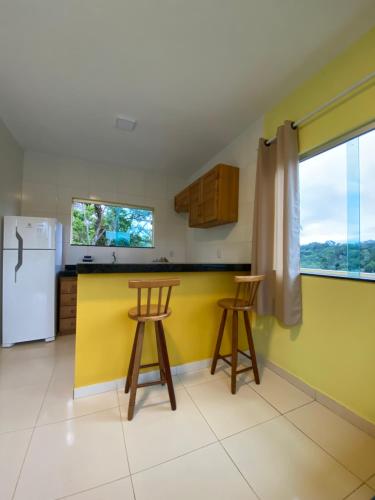 a kitchen with two bar stools and a refrigerator at Residencial Sítio Paraíso in Itacaré