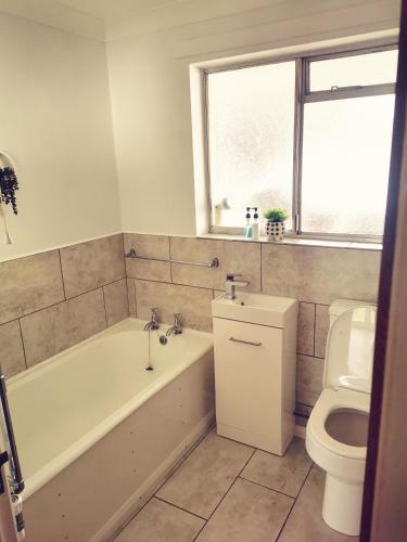 a bathroom with a bath tub and a toilet at Newbrea Room 2 in Axminster