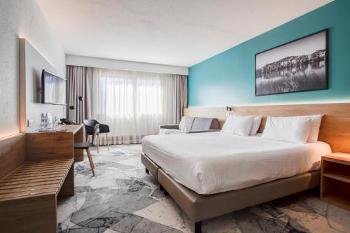 ヴィルールバンヌにあるホテル デ コングレのベッドとデスクが備わるホテルルームです。