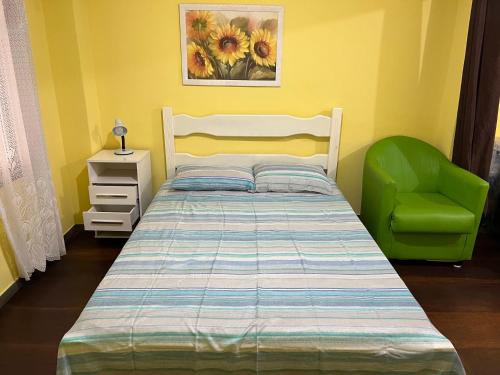 - une chambre avec un lit et une chaise verte dans l'établissement Anjos Dourados Apartment, à Mangaratiba