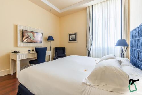 a hotel room with a white bed and a desk at HOTIDAY Room Collection - Livorno Mascagni in Livorno