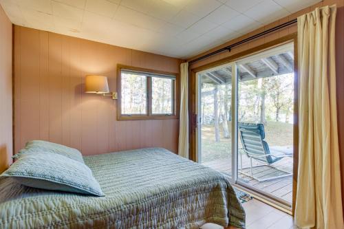 1 dormitorio con 1 cama y patio con silla en Lakefront Park Rapids Cabin with Grill and Fire Pit! en Park Rapids