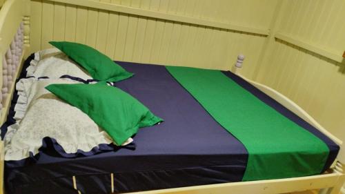 Una cama con almohadas verdes y blancas. en Pousada Flor da Serra en Urubici