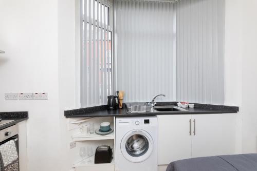 a kitchen with a washing machine and a sink at No 1 Thornhill House in Hartlepool