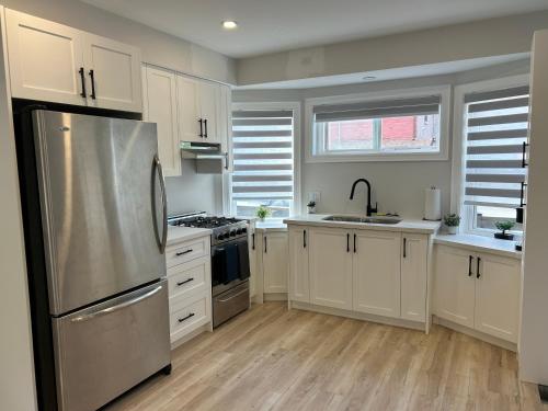 kuchnia z białymi szafkami i lodówką ze stali nierdzewnej w obiekcie Brand New Home in Hamilton w mieście Hamilton