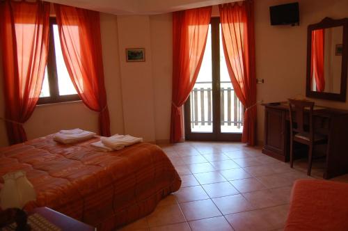 a bedroom with a bed and windows with red curtains at B&B La Tana Dell'orso in Villalago