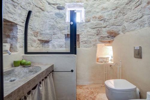 a stone bathroom with a toilet and a sink at Trullo Cristiana in Latiano