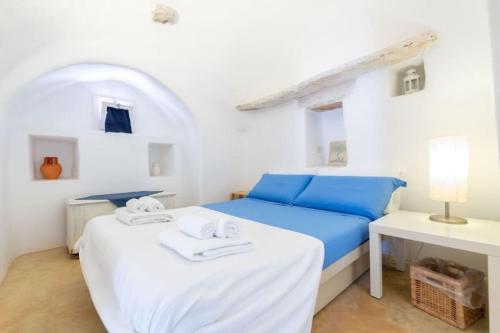 a white bedroom with a blue bed and a desk at Trullo Cristiana in Latiano