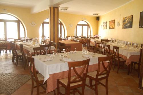 uma sala de jantar com mesas, cadeiras e janelas em B&B La Tana Dell'orso em Villalago