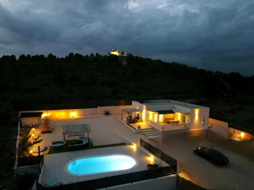a house with a swimming pool at night at Villa VERONICA with CINEMA PROJECTOR by the HEATED POOL and JACUZZI in Šibenik